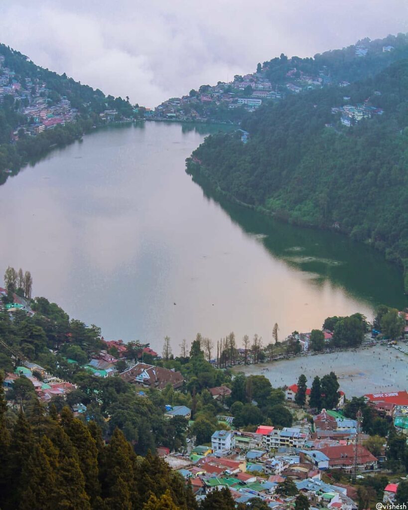 alt="A soft feather in the foreground with the tranquil Nainital Lake and surrounding hills in the background, symbolizing the peaceful charm of Nainital's top sightseeing spots."