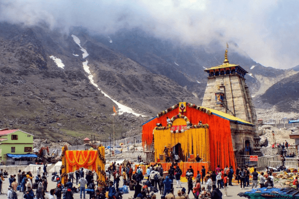 Group of happy pilgrims posing in front of Kedarnath temple.