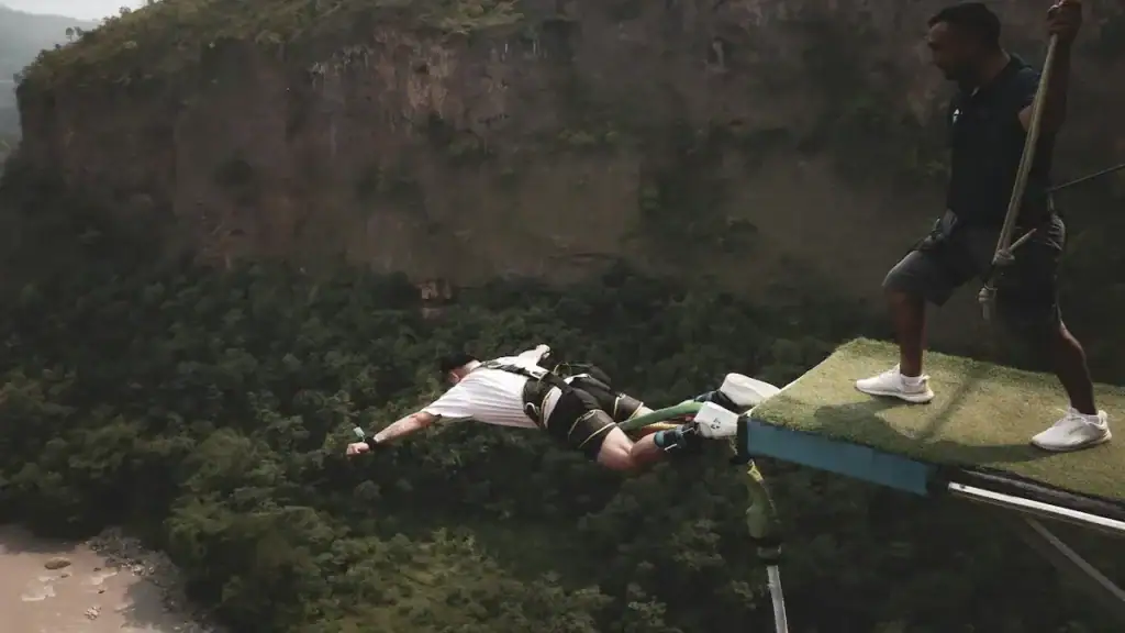 Person doing bungee jumping in Nainital surrounded by green mountain valleys