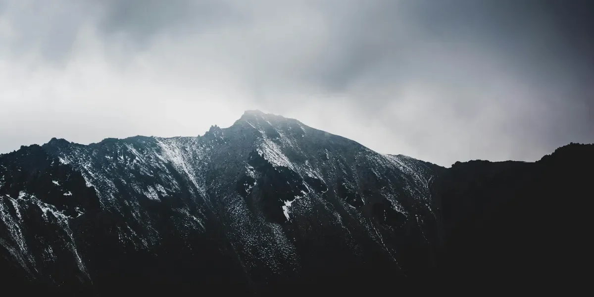 Grey mountain landscape in Nainital with light snowfall and cloudy winter skies