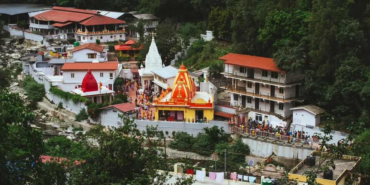 Aerial view of Kainchi Dham Neem Karoli Baba Ashram in Uttarakhand surrounded by green hills.